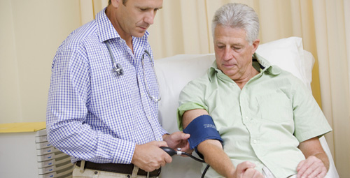An older man being given a blood pressure test by a doctor